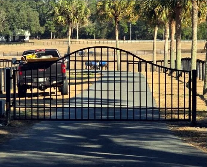 Finished black metal entrance gate spanning a driveway