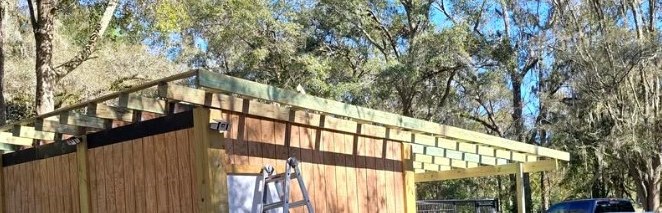 Wood-framed roof extension attached to an outdoor structure