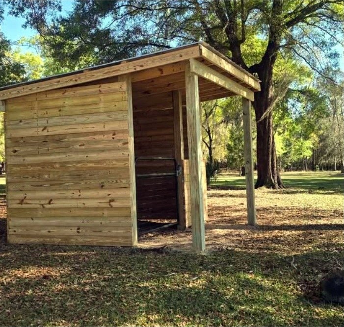 Wide view of a completed wooden shelter in a pasture